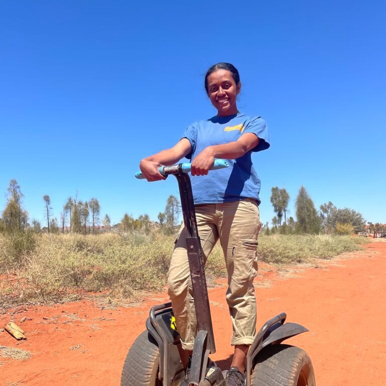Uluru_Segway_Tours_Guide_Milika Milika poses on her Segway with an endless blue sky behind her.